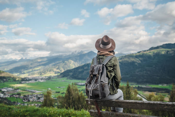 Wanderin sitz auf einer Bank und blickt auf die Alpenlandschaft